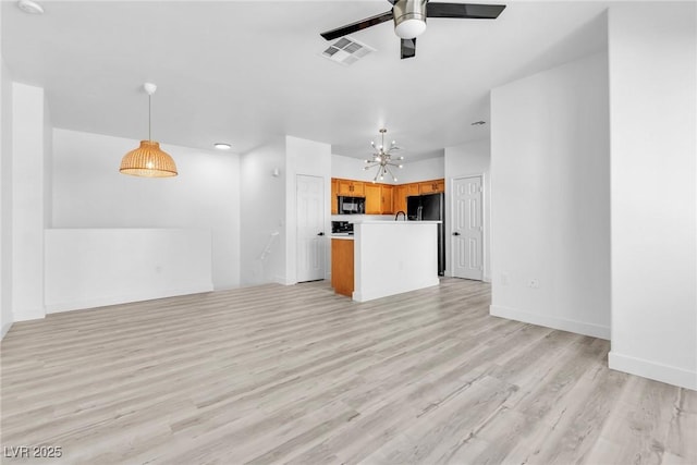 unfurnished living room with light wood-type flooring, visible vents, baseboards, and ceiling fan with notable chandelier