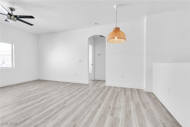 unfurnished room with light wood-style flooring, arched walkways, baseboards, and ceiling fan