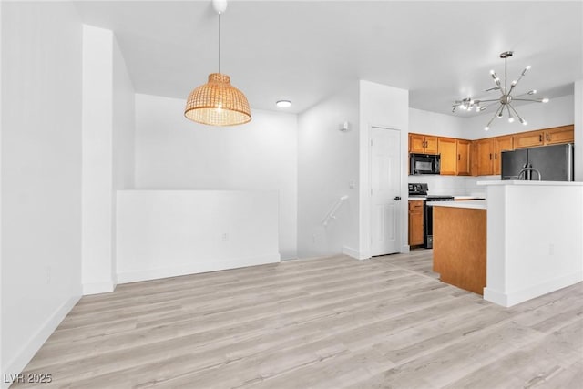 kitchen featuring hanging light fixtures, black appliances, brown cabinets, and light wood-type flooring