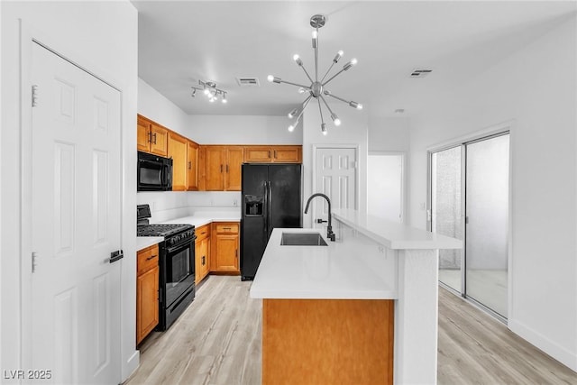 kitchen featuring visible vents, a sink, black appliances, light countertops, and a chandelier