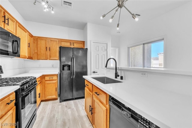 kitchen featuring black appliances, light countertops, visible vents, and a sink