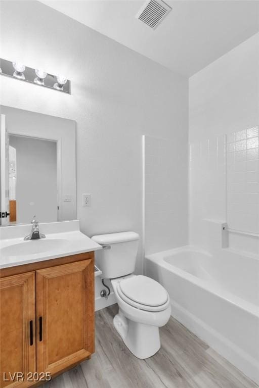 bathroom with vanity, toilet, wood finished floors, and visible vents