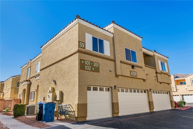 view of building exterior with an attached garage and central AC