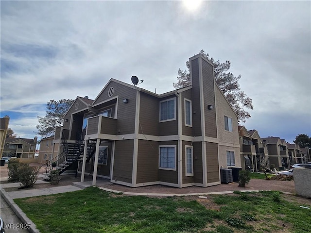 back of property with a residential view, stairs, cooling unit, a chimney, and a yard