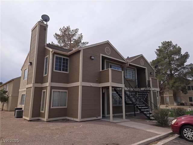 view of front of home featuring stairway, central AC, and a chimney