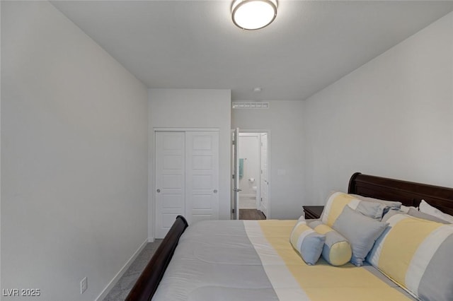 bedroom with baseboards, a closet, dark carpet, and connected bathroom