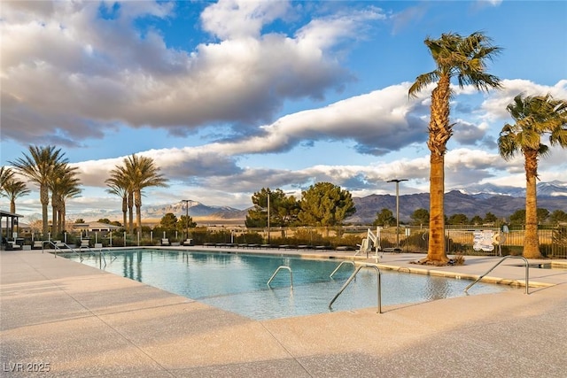 pool with a mountain view, a patio, and fence