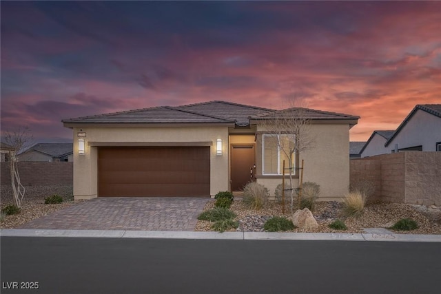 view of front of home with stucco siding, an attached garage, decorative driveway, and fence