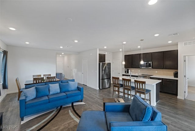 living room with dark wood-type flooring, recessed lighting, visible vents, and baseboards