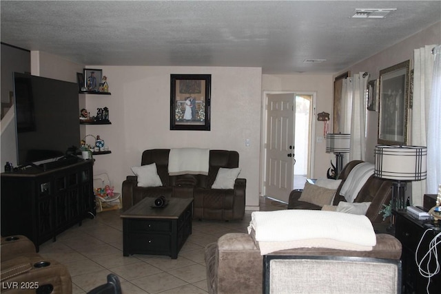 living room with visible vents, a textured ceiling, and light tile patterned flooring