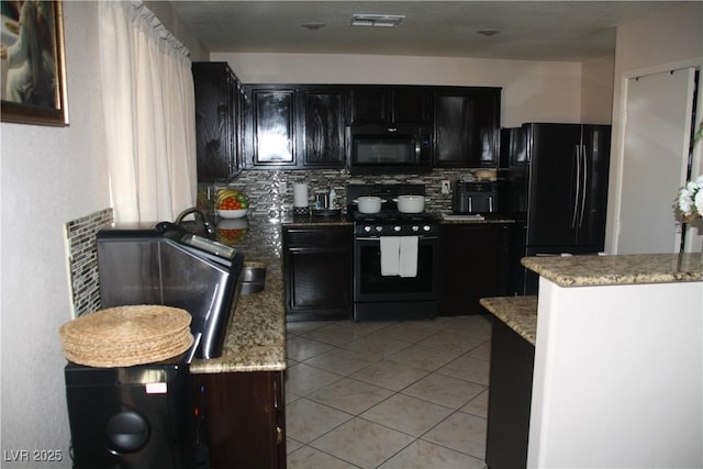 kitchen featuring light stone counters, light tile patterned floors, visible vents, black appliances, and tasteful backsplash