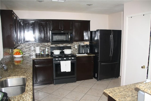 kitchen featuring light stone counters, decorative backsplash, light tile patterned flooring, black appliances, and a sink