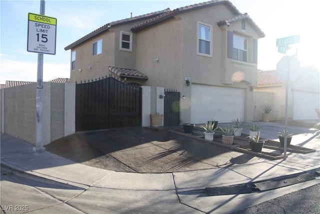 view of front of property with stucco siding, a tiled roof, concrete driveway, and fence