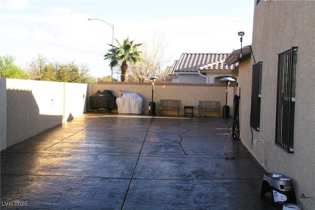 view of patio with fence and a grill