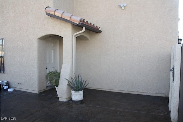 entrance to property featuring a tile roof and stucco siding