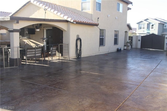 rear view of property with stucco siding, fence, and a tile roof