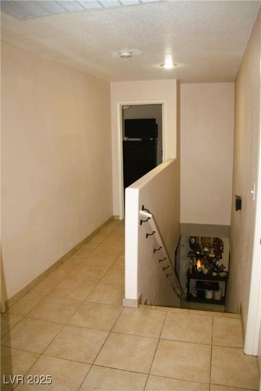 hallway with light tile patterned flooring and baseboards