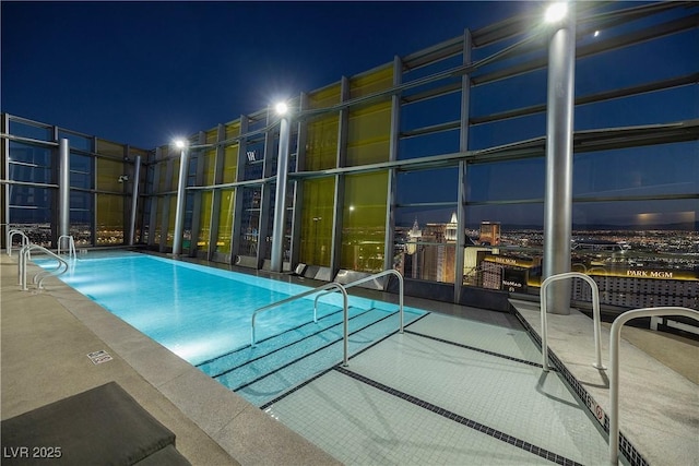 pool at night featuring a community pool and fence