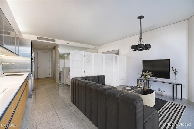 living room featuring visible vents, light speckled floor, and an inviting chandelier