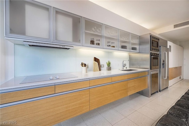 kitchen featuring visible vents, a sink, stainless steel appliances, light countertops, and glass insert cabinets