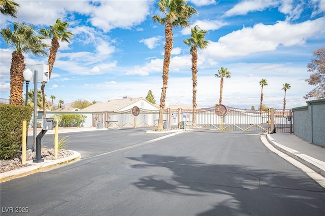 view of street featuring sidewalks, curbs, a gated entry, and a gate