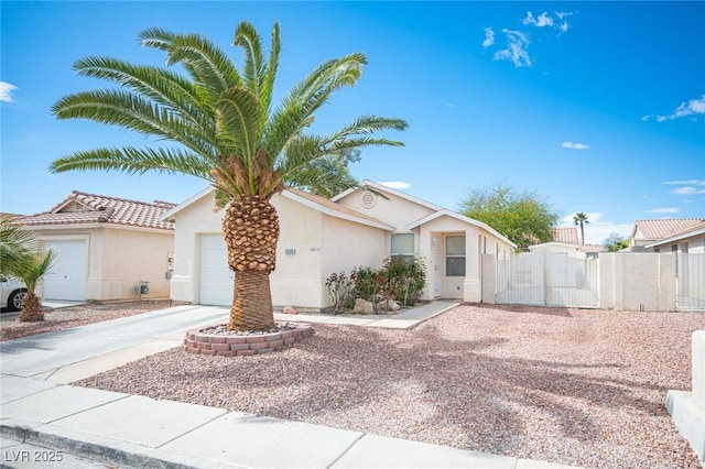 view of front of home with fence, stucco siding, a garage, driveway, and a gate