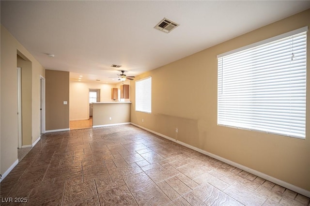 spare room featuring visible vents, baseboards, stone tile flooring, and a ceiling fan