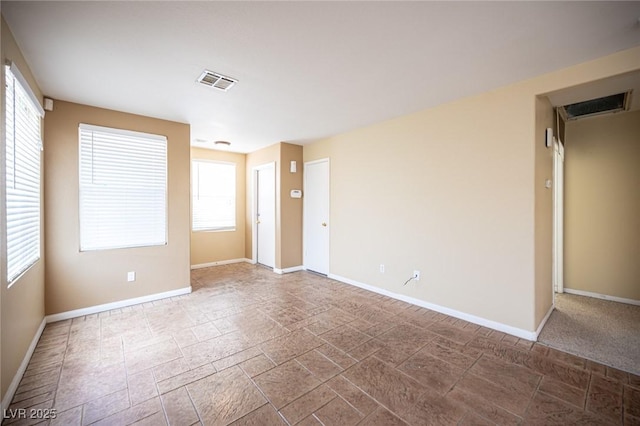 empty room featuring visible vents, stone finish flooring, and baseboards