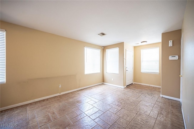 unfurnished room with stone tile floors, visible vents, and baseboards