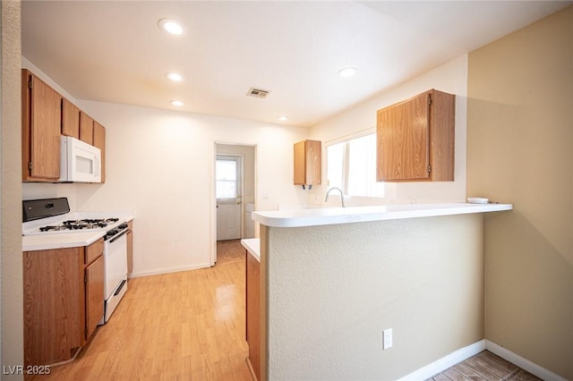 kitchen featuring visible vents, white appliances, light countertops, and light wood-style floors