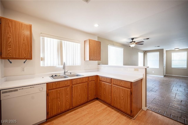 kitchen with visible vents, a peninsula, a sink, light countertops, and dishwasher