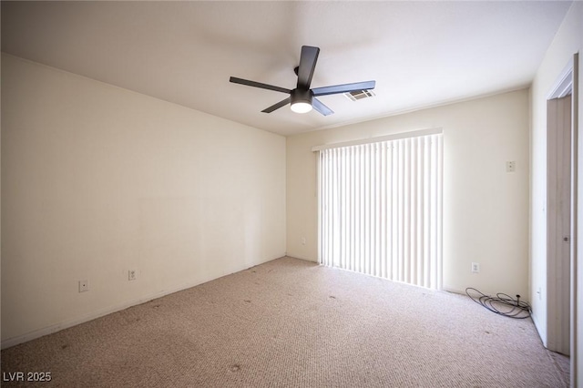 empty room with visible vents, plenty of natural light, carpet, and a ceiling fan