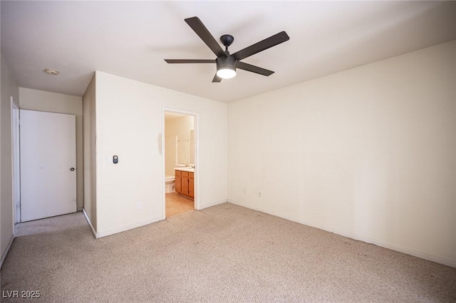 unfurnished bedroom featuring light colored carpet, ensuite bath, baseboards, and a ceiling fan