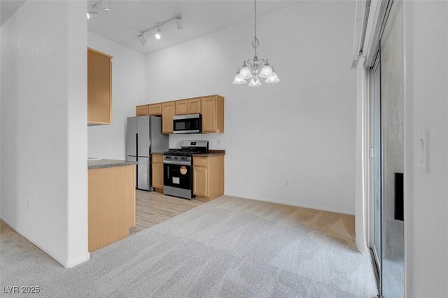 kitchen featuring track lighting, appliances with stainless steel finishes, an inviting chandelier, light colored carpet, and a towering ceiling