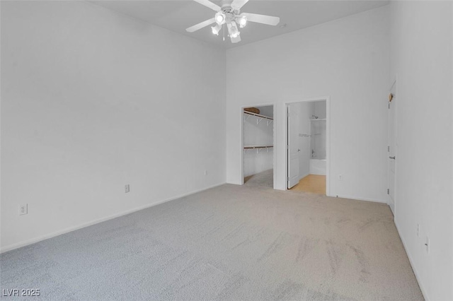 unfurnished bedroom with baseboards, a ceiling fan, a spacious closet, and carpet flooring