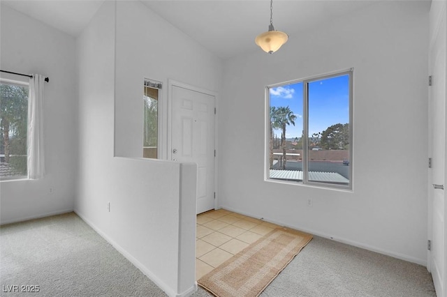 tiled spare room featuring baseboards and carpet floors