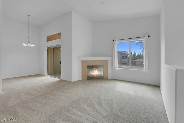 unfurnished living room featuring carpet flooring, a fireplace, a high ceiling, and an inviting chandelier