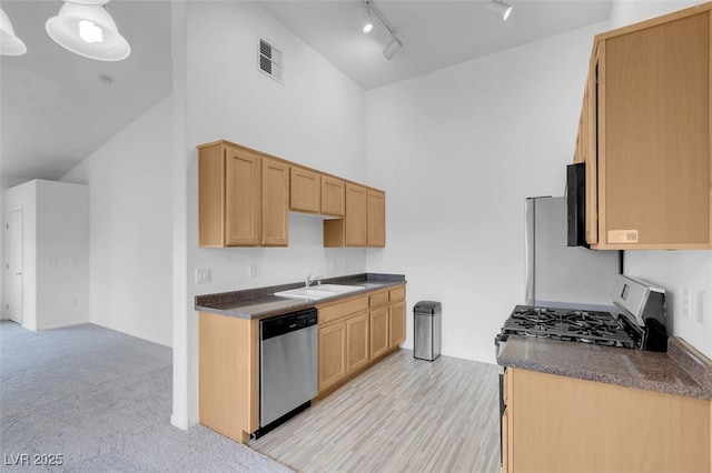 kitchen with visible vents, a sink, dark countertops, stainless steel appliances, and a high ceiling