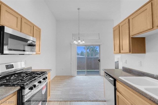 kitchen with a sink, appliances with stainless steel finishes, light brown cabinets, and an inviting chandelier