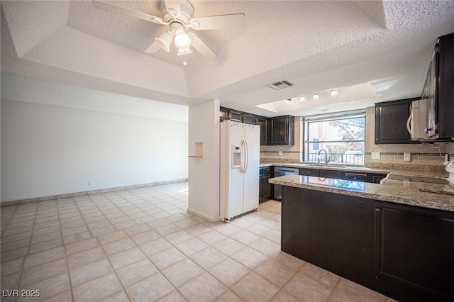 3369 Milenko Dr, Las Vegas, NV 89121 - kitchen featuring white refrigerator with ice dispenser, a textured ceiling, a tray ceiling, light stone countertops, and a sink
