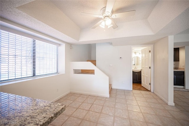 3369 Milenko Dr, Las Vegas, NV 89121 - unfurnished living room with ceiling fan, a textured ceiling, a tray ceiling, and baseboards
