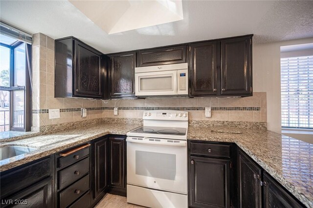 3369 Milenko Dr, Las Vegas, NV 89121 - kitchen featuring white appliances, tasteful backsplash, light stone counters, and dark brown cabinetry