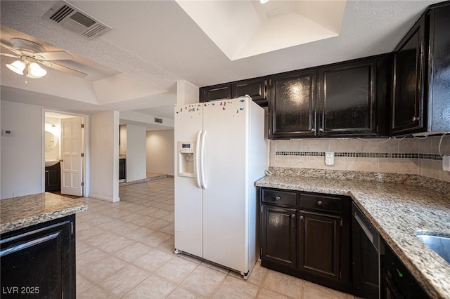 3369 Milenko Dr, Las Vegas, NV 89121 - kitchen with white fridge with ice dispenser, a raised ceiling, a ceiling fan, backsplash, and light stone counters