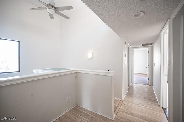 3369 Milenko Dr, Las Vegas, NV 89121 - hall featuring light wood-type flooring, a textured ceiling, baseboards, and an upstairs landing