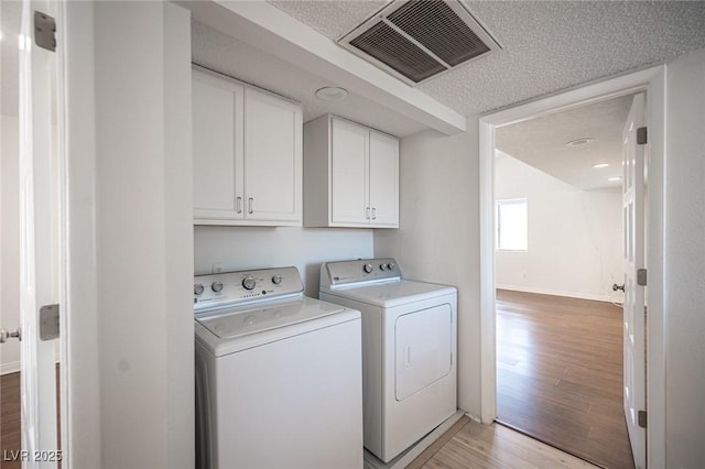3369 Milenko Dr, Las Vegas, NV 89121 - laundry area with separate washer and dryer, light wood-type flooring, cabinet space, and a textured ceiling
