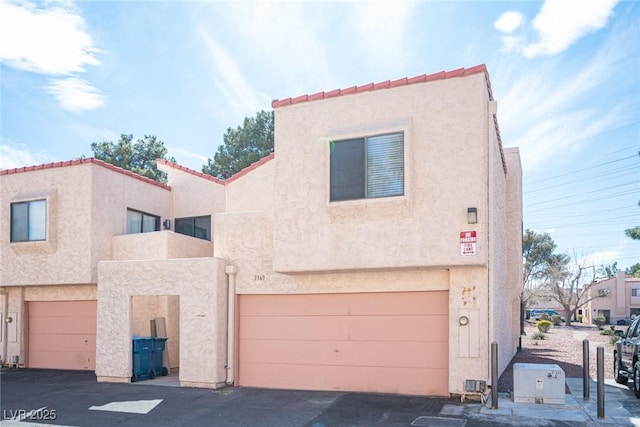 multi unit property with stucco siding, a garage, and a tile roof