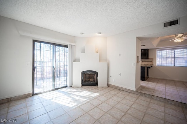 3369 Milenko Dr, Las Vegas, NV 89121 - unfurnished living room with a textured ceiling, a fireplace, light tile patterned floors, and ceiling fan