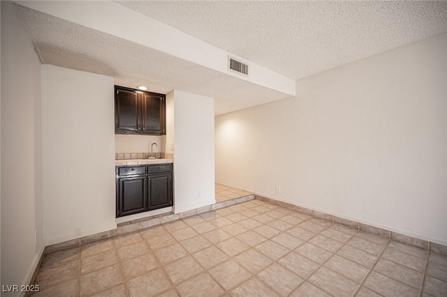 3369 Milenko Dr, Las Vegas, NV 89121 - spare room with a textured ceiling, bar with sink, and baseboards