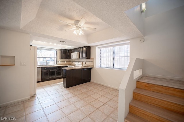 3369 Milenko Dr, Las Vegas, NV 89121 - kitchen featuring white microwave, a raised ceiling, a ceiling fan, a textured ceiling, and stainless steel dishwasher