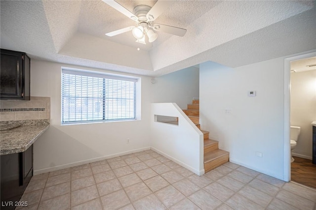 3369 Milenko Dr, Las Vegas, NV 89121 - unfurnished dining area with a ceiling fan, a tray ceiling, a textured ceiling, stairs, and baseboards